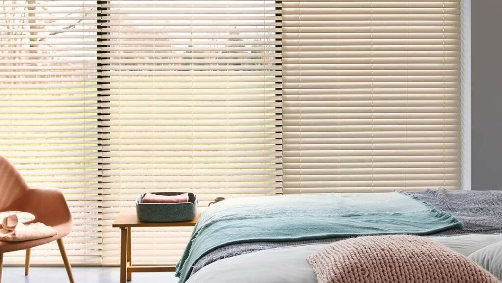 Cozy bed room with large windows and natural light featuring Timber Blinds by Luxaflex. Window covering ideas by rooms.