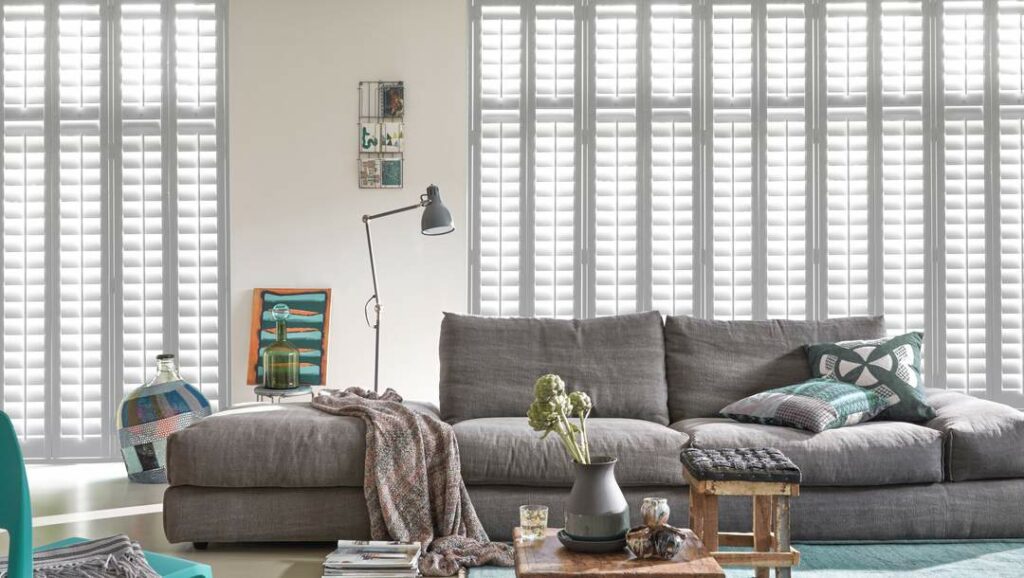 White Wood Shutters by Luxaflex in a bright and cozy living room. Shutters for Sliding Doors.