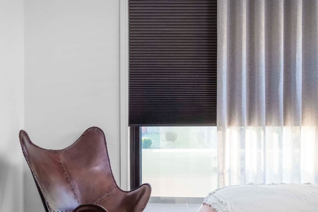 Close-up of dark brown Luxaflex Duette Shades in combination with Luxaflex Sheer Curtains. 