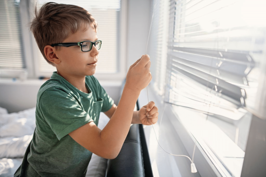 Child pulling on window curtain/blind cord.