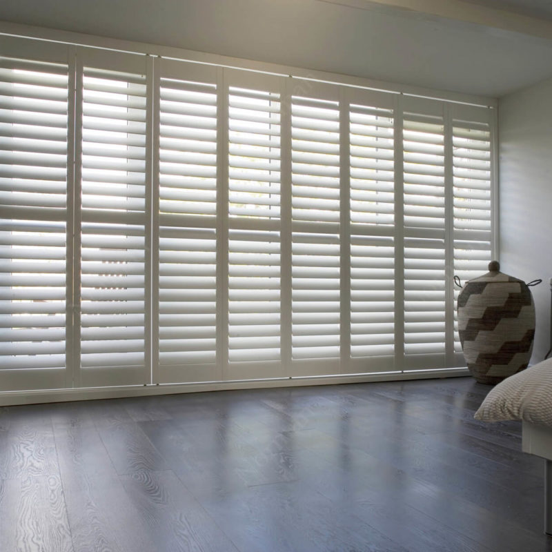 a bedroom with white shutters and a bed