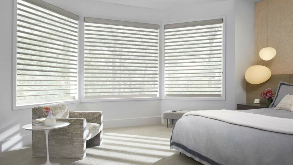Pirouette shades installed in a white and cozy bed room. Matching white blinds with white walls design.