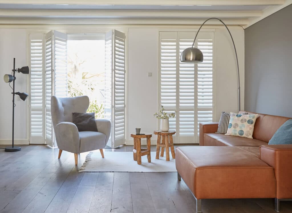 Plantation shutters that dampen noise, installed in a modern and eclectic cozy living room.