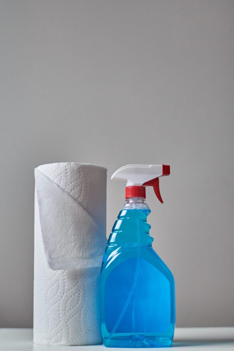 a bottle of cleaning product and a roll of toilet paper on a white background