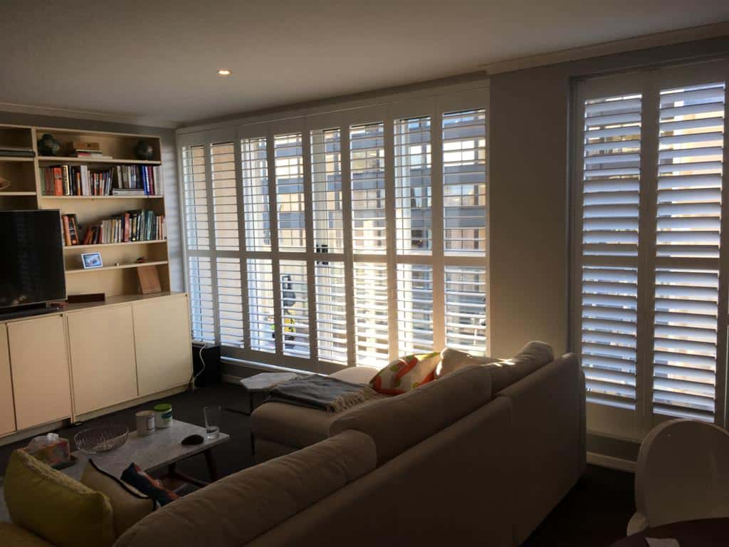 a living room with white shutters and a couch