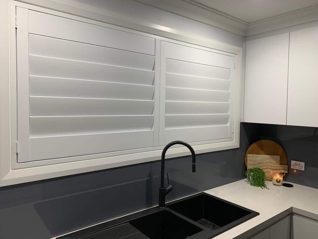a kitchen with white shutters and a sink
