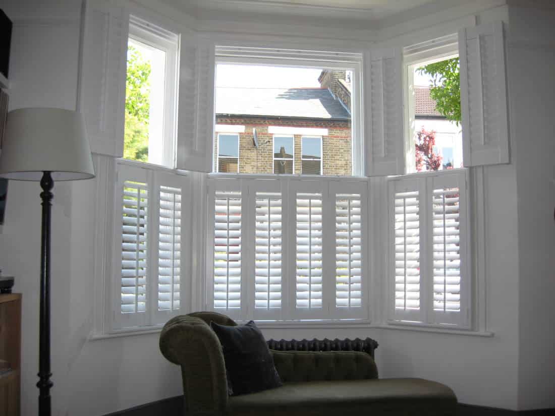 a bay window with shutters and a chair