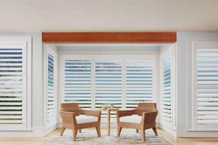 Wooden Aesthetic Living Space With Sliding Doors Revealing Scenic Beach And Nature View, Covered By Luxaflex Polysatin Shutters. For Sale In Complete Blinds Showroom.
