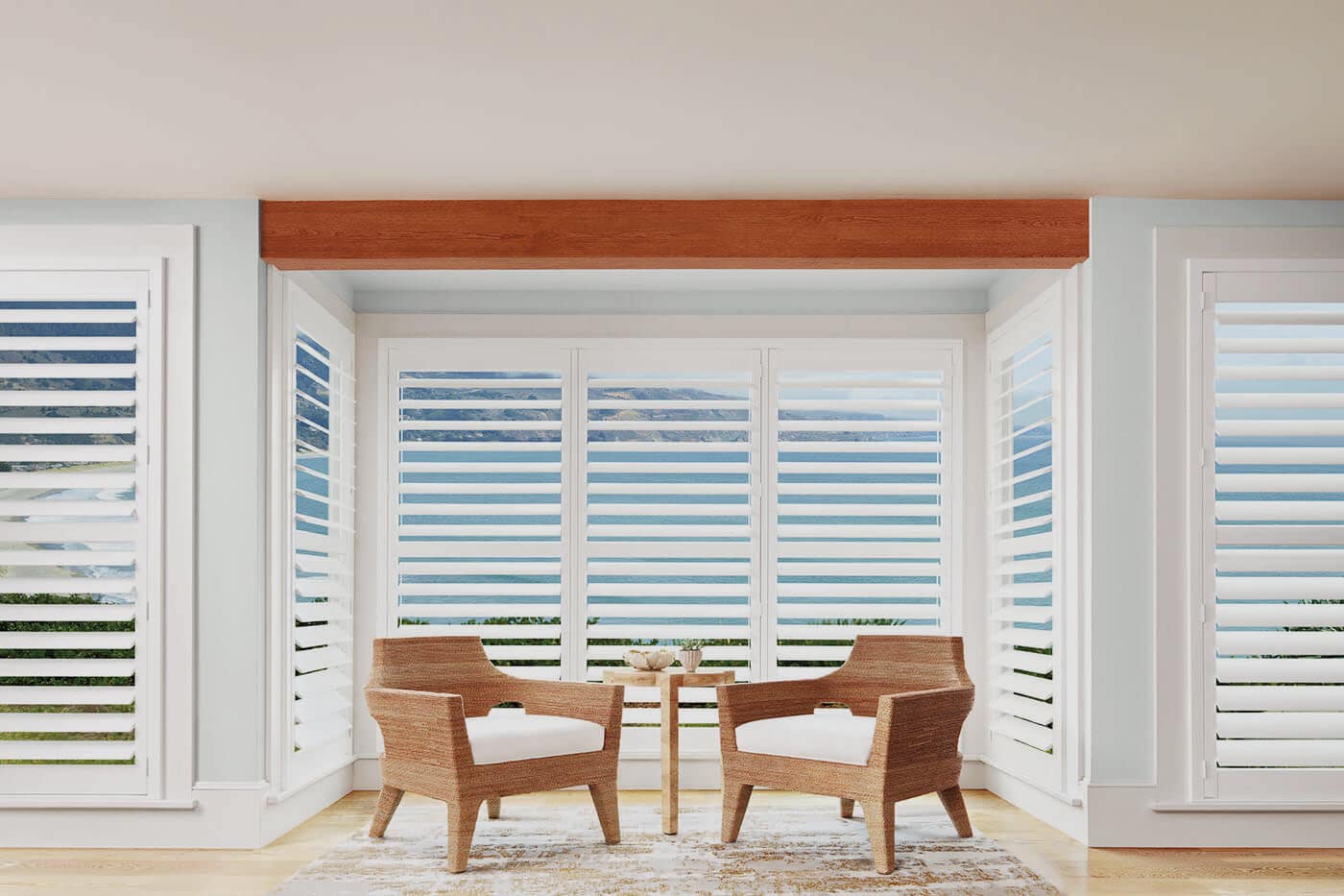 Wooden aesthetic living space with sliding doors revealing scenic beach and nature view, covered by Luxaflex Polysatin Shutters. For sale in Complete Blinds showroom.