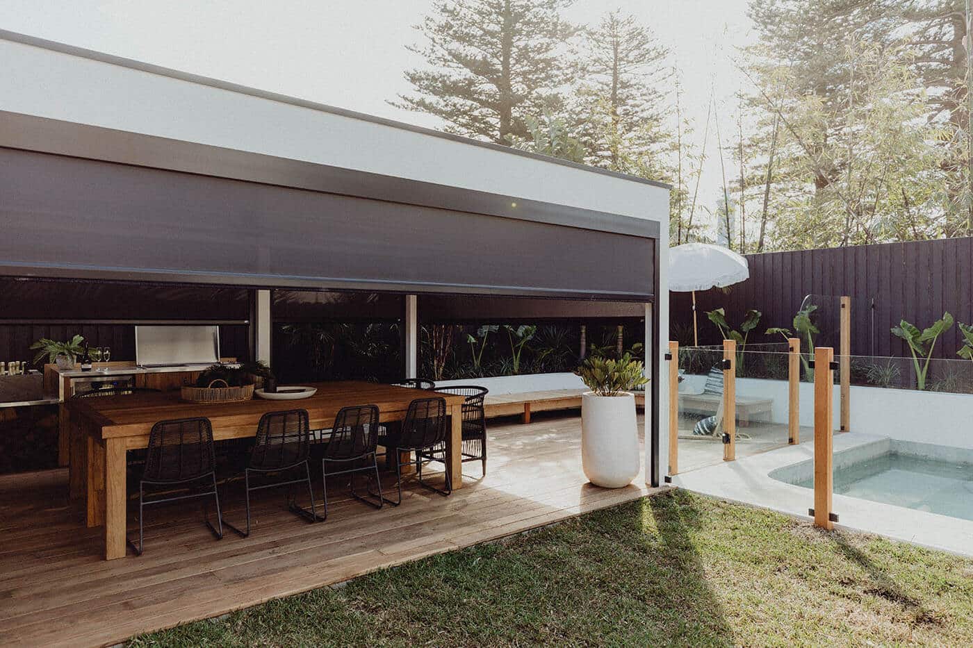 Modern luxurious home with dining area at the patio, featuring dark grey Evo Magnatrack Awnings by Luxaflex.
