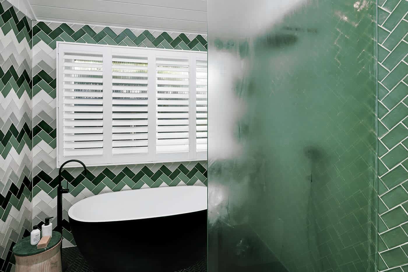 Contemporary green bathroom featuring water-resistant Luxaflex matte white Polysatin Shutters, suitable for wet areas such as kitchen and bathroom. Made in Australia.