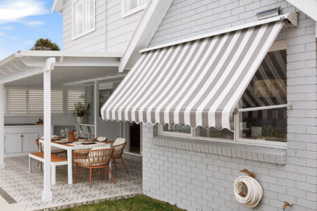 Outside View Of A Home Patio And Garden With Mid-century Design Style, Featuring Luxaflex System 2000 Awning Covering A Big Window Pane, Providing Shade And Blocking Out Sunlight. On Display In Our Sydney Showroom.