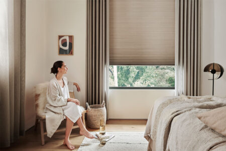 Contemporary Room With Brown Tones, With A Lady Sitting Comfortably On A Chair Looking Through The Window. Luxaflex Duette Shades Partially Covering The Window. For Sale In Our Sydney Showroom.