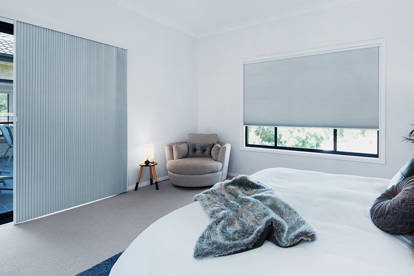 Motorised Portrait Honeycomb Shades by Norman covering windows in a white bedroom, available in various fabric design and opacity. Made in Australia.