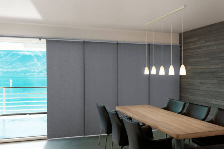 Modern Dining Area With Dark Wooden Walls And Tables, Featuring Luxaflex Panel Glide Blinds Covering Large Window Panes, Block Out Natural Sun Light. Made In Australia.