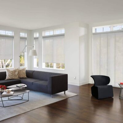 Wide Contemporary Living Space With Modern Furniture Designs, Featuring Luxaflex Panel Glide Blinds Cover Several Large Window Panes, Diffusing Natural Light Into The Room.