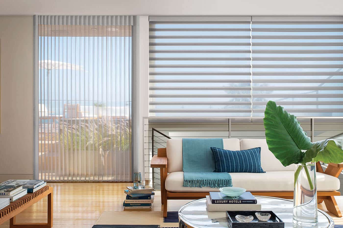Translucent Luxaflex Pirouette Shades in a vibrant home living room, vaguely showing scenic view of the oceanic outdoors through large windows.