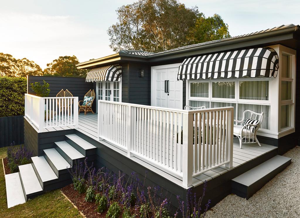 Mid-century home design featuring window installed with black and white striped Luxaflex Awnings.