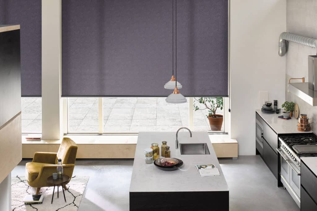 Large dark grey Roller Blinds by Luxaflex installed in a modern and contemporary kitchen space with large windows. Available at Complete Blinds Sydney. 