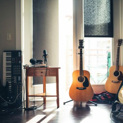Guitars, Musical Instruments, And Records In A Room, Signifying Noise, And Featuring Blinds That Dampen Noise.